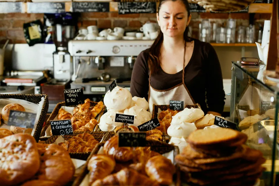 Boulangère derrière son comptoir garni de croissants, brioches et meringues